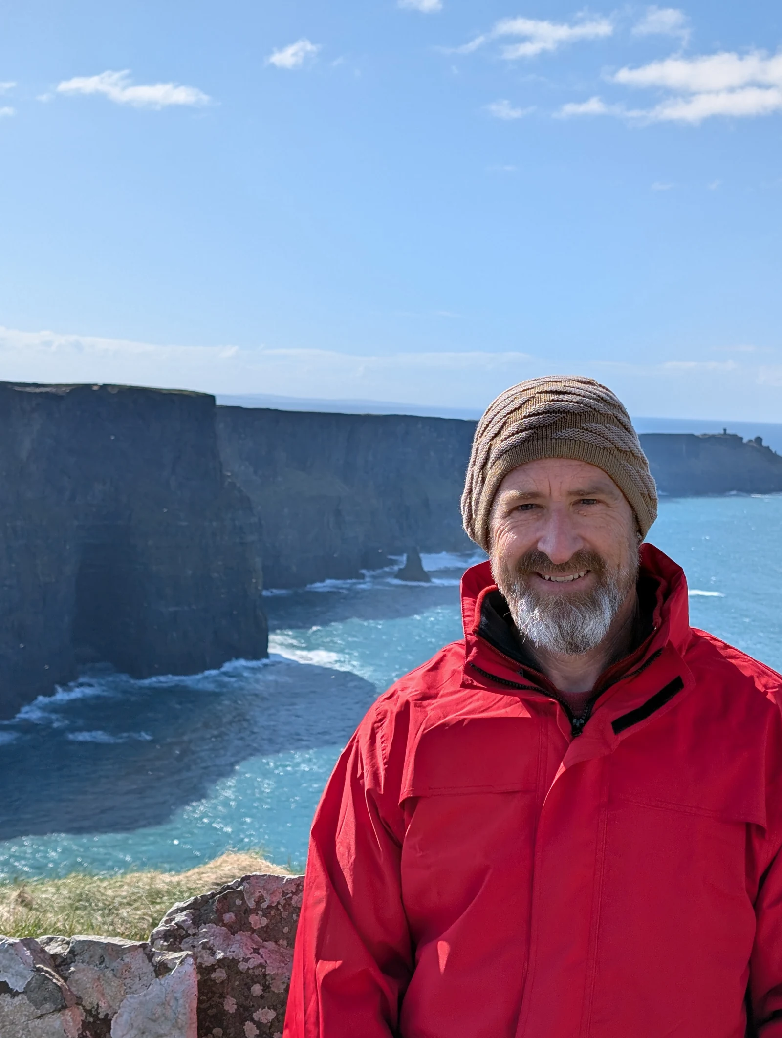 Rowdy Taylor in a red jacket beside the sea cliffs.