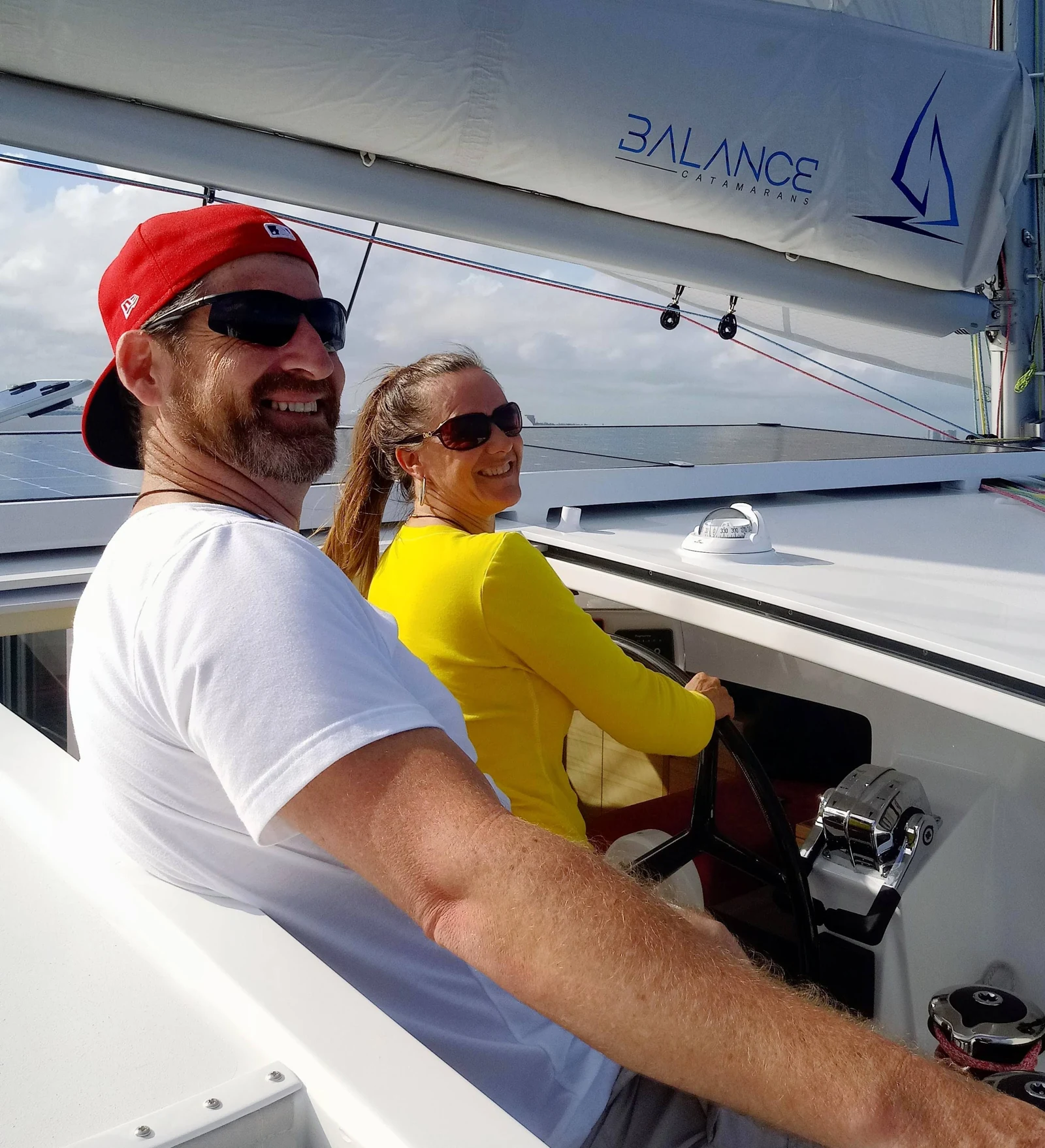 Rowdy and Jennifer smiling together at the helm of a Balance 526 sailing catamaran.